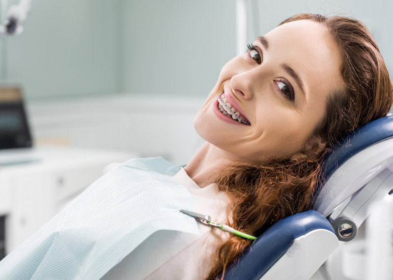 smiling woman with braces in an orthodontic chair