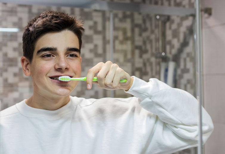 teenage boy brushing his teeth in the bathroom