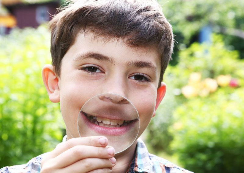 a boy holding a magnifying glass to his teeth