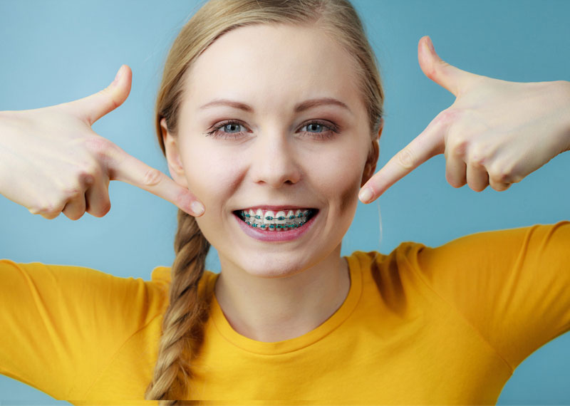 smiling teen girl pointing to her braces